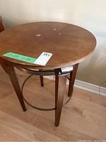 Front angle view of round wooden side table showing surface wear and metal base ring