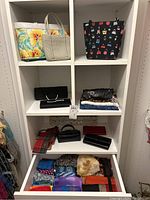Shelf showing the full collection of bags, wallets, scarves and accessories arranged on shelves and in a drawer.