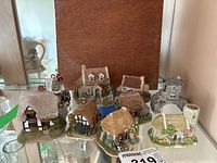Display of approximately nine Lilliput Lane miniature cottages with various roof styles and detailed paintwork.
