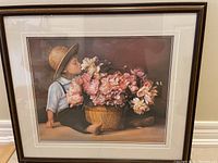 Framed print of Amish boy sitting next to basket of pink flowers, showing full frame and matting.