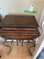 Front view of decorative wooden occasional table with a hinged top and drawer, standing on ornate metal legs with claw feet.