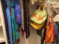 Full view of hanging scarves, purses and hat showing the lot composition.