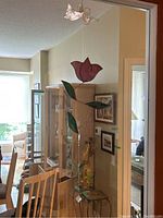 Photo showing pink stained glass rose with green leaves attached to wire frame on top of cabinet.