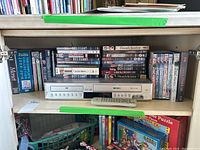 Shelf shot showing Toshiba DVD/VHS player with remote in front. Surrounding DVDs include Doctor Martin series, DCI Banks, Law & Order UK, Grantchester and more.