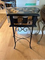 Front view of the occasional table showing abstract inlay on top and drawer front, metal frame base with curved legs and scrollwork.