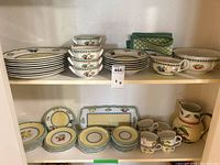 Full shelf view showing assorted plates, bowls, cups and serving pieces.