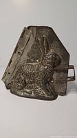 Front side of the antique metal rabbit chocolate mold showing the detailed relief of a sitting rabbit.