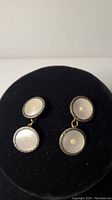 Pair of vintage Art Deco cuff links displayed on black velvet, showing both top and bottom discs with mother of pearl and seed pearl centers.