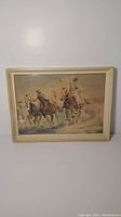 Framed watercolour painting showing cowboy and horses in motion