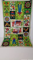 Photo of full Pennsylvania Dutch linen tea towel hung vertically showing all design panels in bold colors.