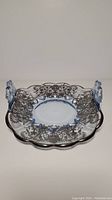 Full top and front view of the sapphire blue glass dish with ornate sterling silver overlay and handles.