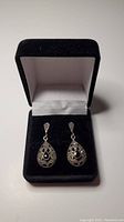 Pair of sterling silver drop earrings with marcasite stones and a central obsidian stone inside a black velvet jewelry box