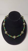Front view of Venetian glass beaded necklace on black neck display form showing beads and overall length.
