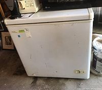 Front view of white Danby Design chest freezer showing slight surface wear, scratches, and control dial.
