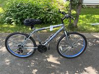 Side profile of Evolution Ozark Trail mountain bike showing frame, wheels with blue accents, and seat.