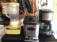 Image showing all three kitchen appliances: Phillips blender on the left with yellow base, Hometrends deep fryer in the middle with stainless steel body, and GE coffee maker on the right with glass carafe.