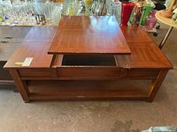 Photo of wood veneer coffee table with lift-top closed, showing surface condition with visible wear, chips, and scratches.