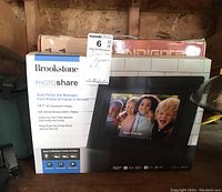 Two digital photo frames in original boxes; one Pandigital 11in and one Brookstone Photo Share 10.1in. Boxes show product branding and screen images.