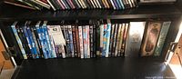 Shelf with approximately 20 DVDs showing variety of movie titles including Star Wars, Indiana Jones and others