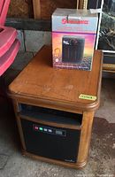 Duraflame movable heater with wooden cabinet and push button controls next to the boxed Super Furnace ceramic heater on wooden table