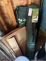 Photo shows folded green carrying case with Ladder Bags branding alongside cardboard box and bag inside a garage setting.