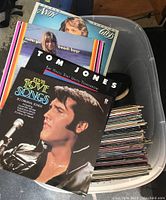 Photo of plastic tote filled with vinyl LP records, showing covers of Elvis Presley, Tom Jones, Beach Boys, and others on top.