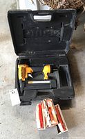 Bostitch brad nailer in black carrying case with several opened boxes of brad nails on the ground in front.