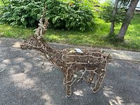 Full view of the outdoor deer figure constructed from sticks with lights, showing antlers and full body shape on driveway outdoors.