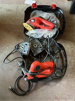 Overview photo showing both the red and black Black & Decker Mega Mouse corded sander with sanding attachments and the red and black ZipSaw corded jigsaw placed inside a black carrying case with red clasps.