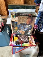 Stack of puzzles, art kits including Copperfoil engraving leopard art kit, baseball themed puzzle, and Thomas Kinkade puzzle box visible.