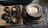 Silver plate goblets, trays, creamer, sugar bowl and dish stands arranged on table and floor showing overall contents and condition with tarnish.