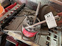 Screwdriver sockets and related socket drivers packed inside a glass container, with a metal crank handle attached beside the container, showing used condition.