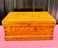 Closed chest showing golden oak finish and wood grain with keyhole in front center of lid.