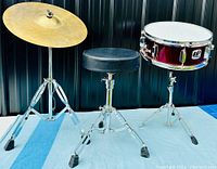 Full view of the drum kit pieces including snare drum, cymbal on a stand, and cushioned black drum stool.
