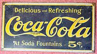 Full view of vintage Coca-Cola metal tin sign with black background and yellow border, featuring text 'Delicious and Refreshing Coca-Cola At Soda Fountains 5¢.'