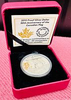 Silver coin in red display box with certificate inside the lid, showing the coin in protective casing.