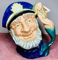 Angled close-up of front face showing detailed sailor head with blue naval cap and mermaid handle