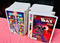Stack of vintage DC comic books showing front covers including Shadow of the Bat and crossover comics with Marvel characters.