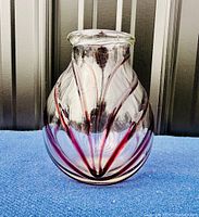 Angled front view of the vintage Murano art glass vase showing its clear glass with brown swirled stripes and bulbous shape with rounded mouth.