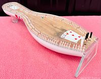 Photo of the vintage cribbage board shaped like a bowling pin showing the wooden playing surface with brass pegs and a clear Lucite stand.