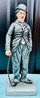Front view of the Charlie Chaplin figurine in his black tuxedo and bowler hat holding a cane.