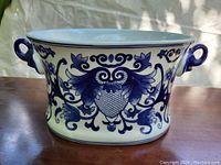Front angle view of the heavy pottery blue and white bowl with detailed blue floral decoration and oval shape.