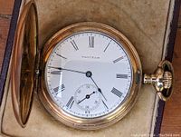 Open watch showing white porcelain dial with Roman numerals, subsidiary seconds at 6, blued steel hands and 'WALTHAM' marking