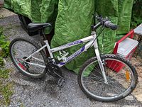 White Super Cycle girls mountain bike with knobby tires and front suspension, shown from angled side view
