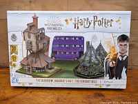 Front of unopened box showing Harry Potter branding and 3D puzzle images of The Burrow, Hagrid's Hut, and The Knight Bus