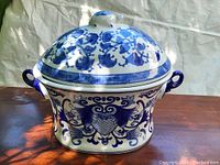 Full front view of the blue and white pottery tureen showing the decorated body and lid with bird handle