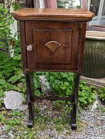 Front view of the walnut small side table cabinet showing door with carved shell and glass knob.