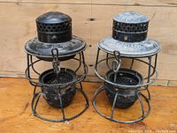 Two vintage CNR lantern metal frames without glass globes or burners, showing age wear and dust on wooden floor.
