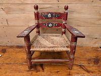 Front view of the vintage child's chair showing hand painted floral design and woven rush seat.