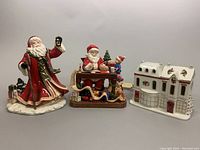Front view of all three porcelain items - Royal Doulton Santa figurine, Royal Albert musical box with Santa, and porcelain Snowy Bake Toy Shop house.